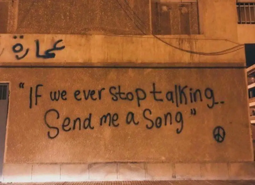 A wall graffiti with the text 'if we ever stop talking, send me a song'